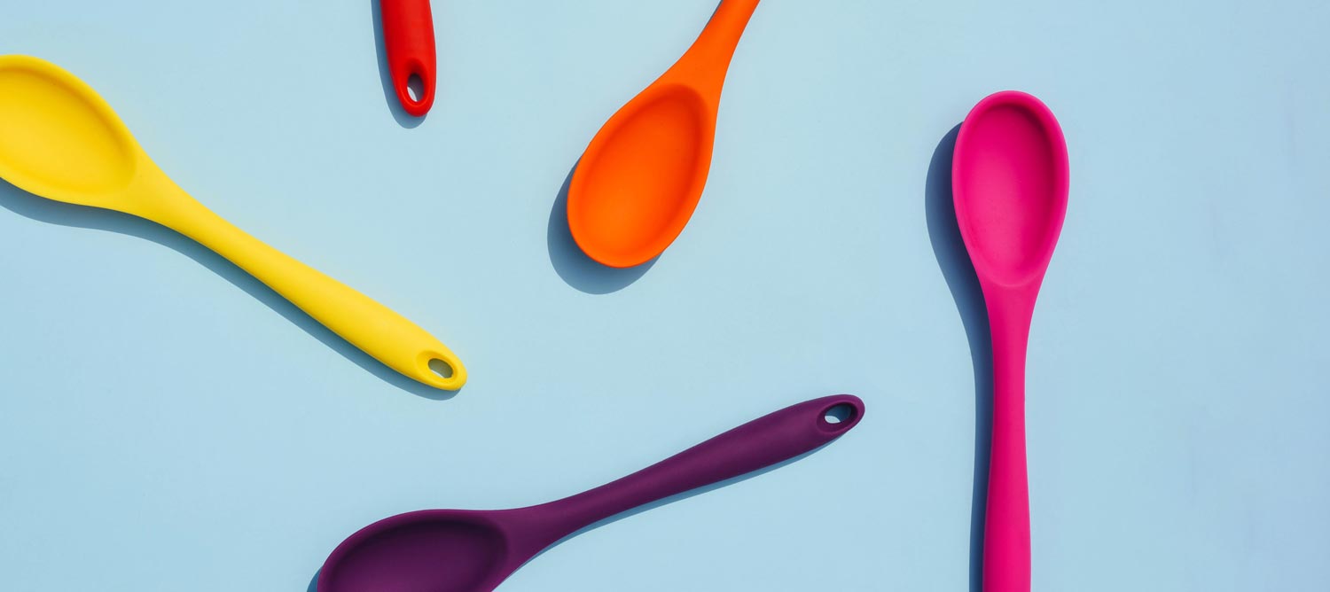 Multi-colored spoons on light blue background