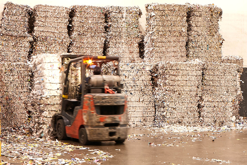 Forklift placing bundle of shredded paper into larger stack in Quad's Sussex recycling center