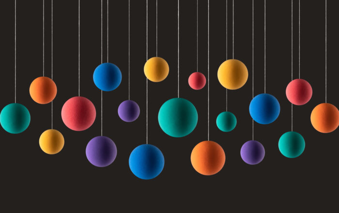Rainbow Colored Spheres or Balls Hanging on Strings Against Dark Gray Background.