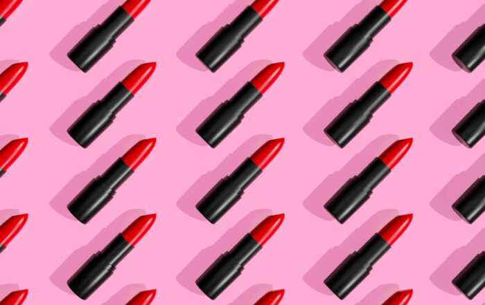Red lipsticks, lip gloss on trendy pastel pink background. Cosmetic products. Makeup accessories. Skin care. Beauty 3D pattern.