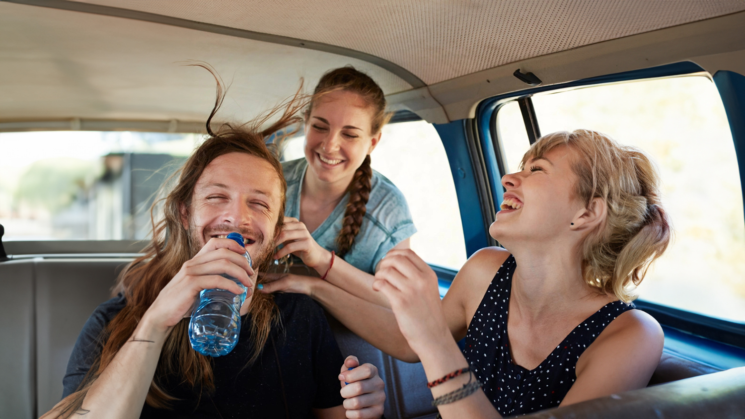 two women and one man laughing in a car