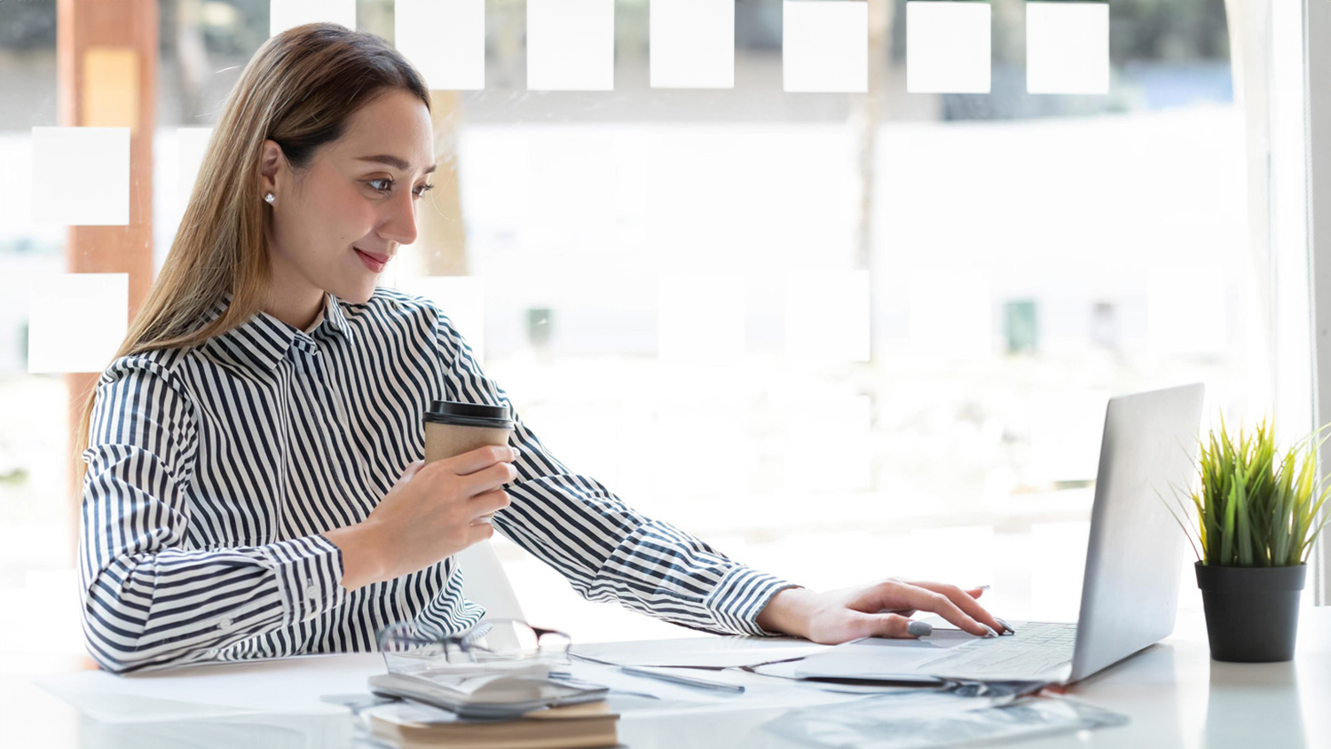 woman looking at laptop with coffee in hand