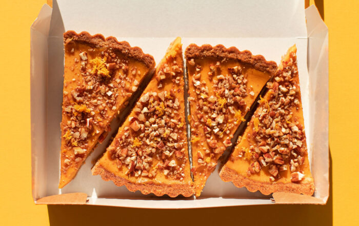 Four pieces of pumpkin cake with walnuts in a cardboard box on a orange table. A traditional autumn dish for Thanksgiving day and Halloween. Flat lay style