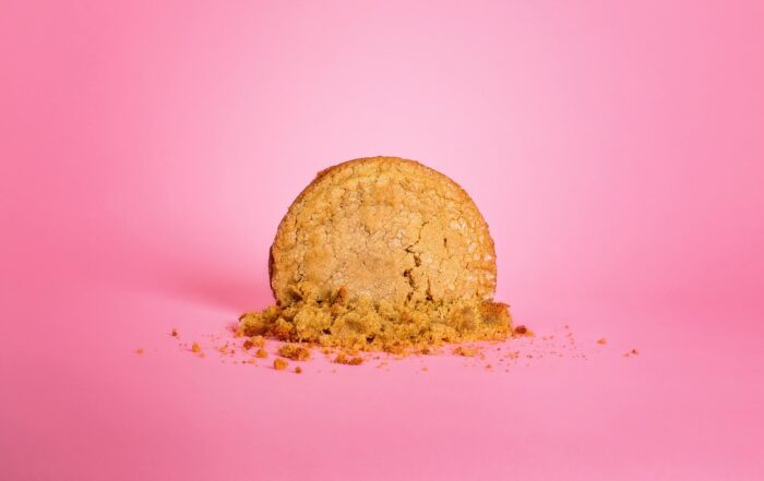 Large smashed homemade vegan, gluten free peanut butter cookie on a pink background