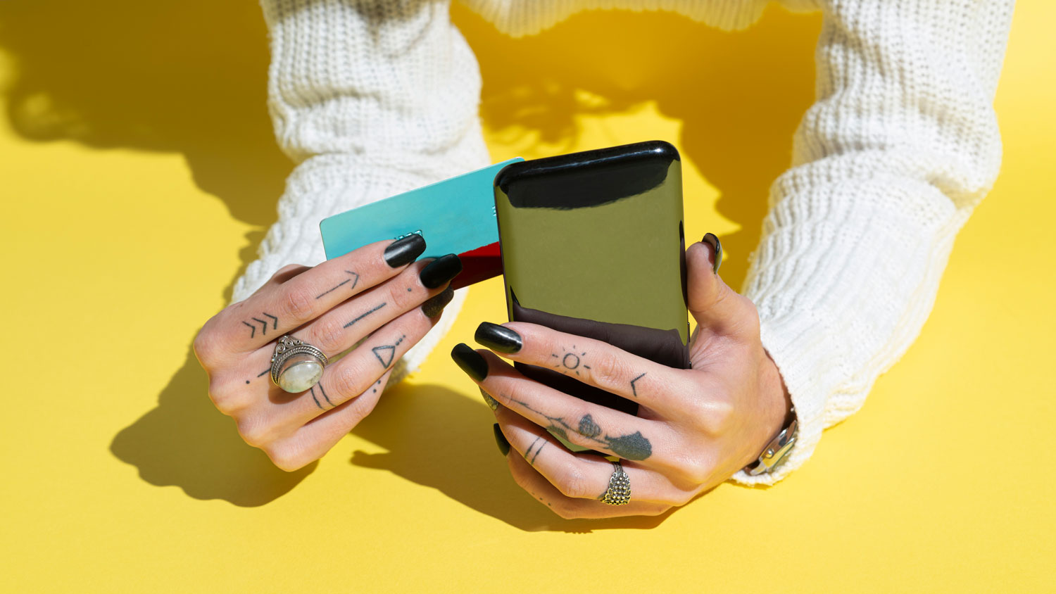 Woman's Hands using credit card for shopping online on her smartphone Over Yellow Background