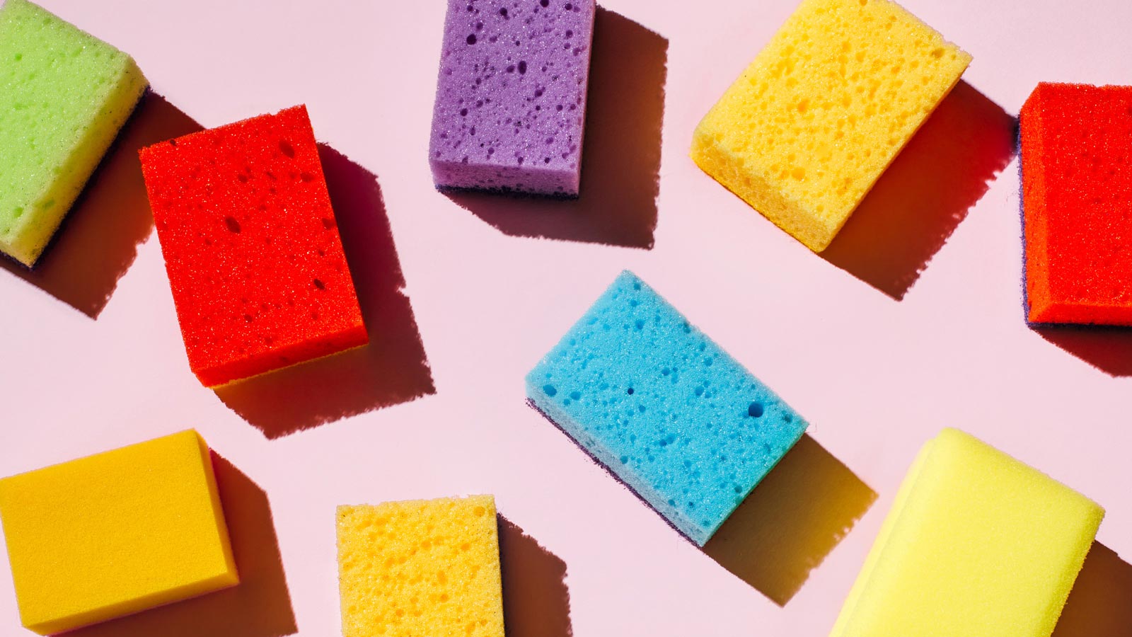 Colored sponges for washing dishes and cleaning on pink background. The concept of cleanliness in the house