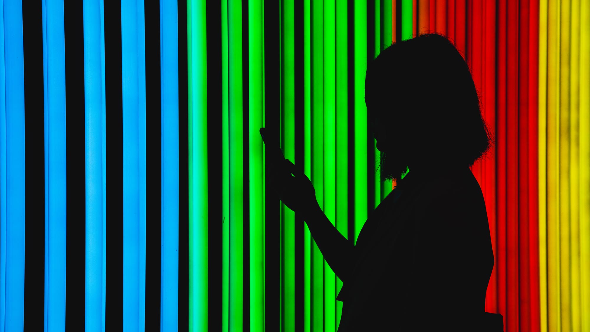 silhouette of woman using phone against neon lights