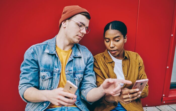 Multicultural male and female checking web article during influence blogging via smartphone devices, millennial hipster guys in trendy streetwear reading promotion publication connecting to 4g on cell