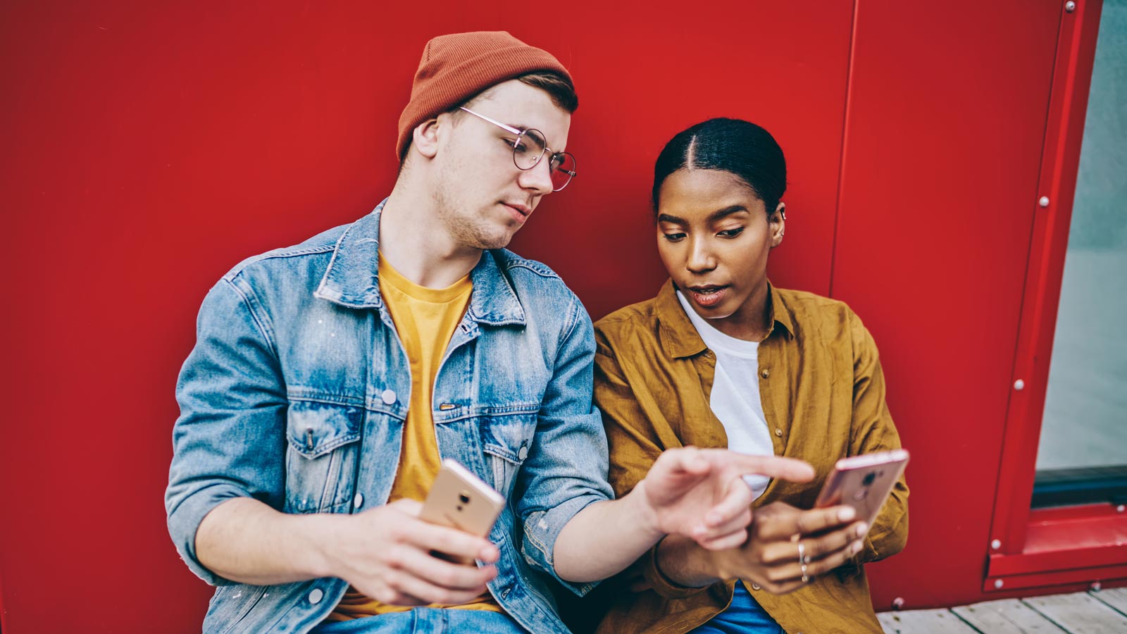 Multicultural male and female checking web article during influence blogging via smartphone devices, millennial hipster guys in trendy streetwear reading promotion publication connecting to 4g on cell