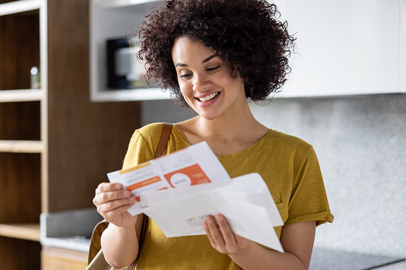 Person holding and looking through direct mail items at home