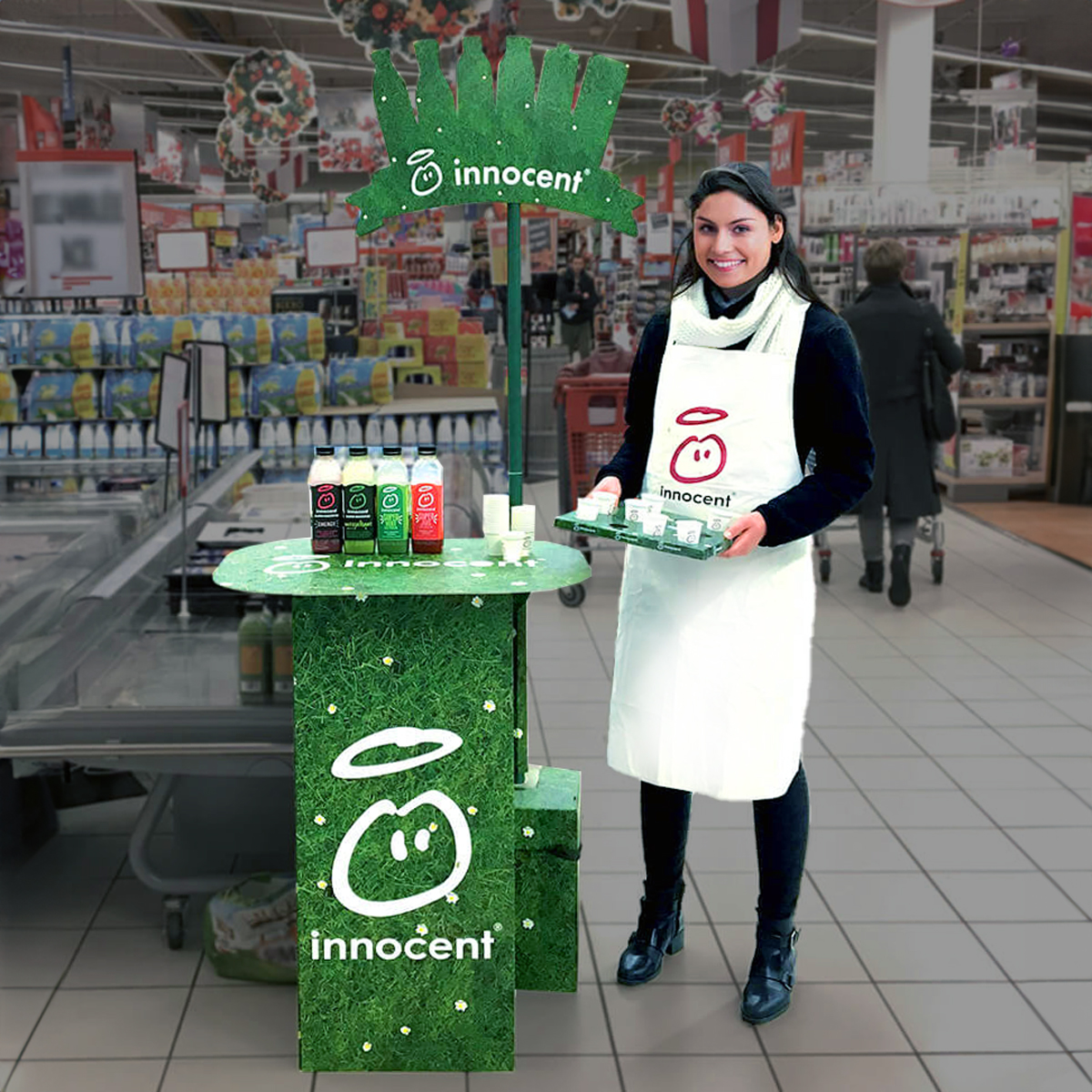Empleado de pie junto a un expositor en la tienda para recibir muestras gratuitas de productos Empleado de pie junto a un expositor en la tienda para recibir muestras gratuitas de productos