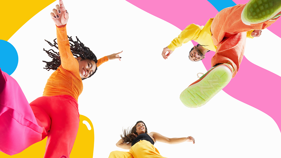 full length studio shot of three people looking down at camera smiling and dancing against colourful background