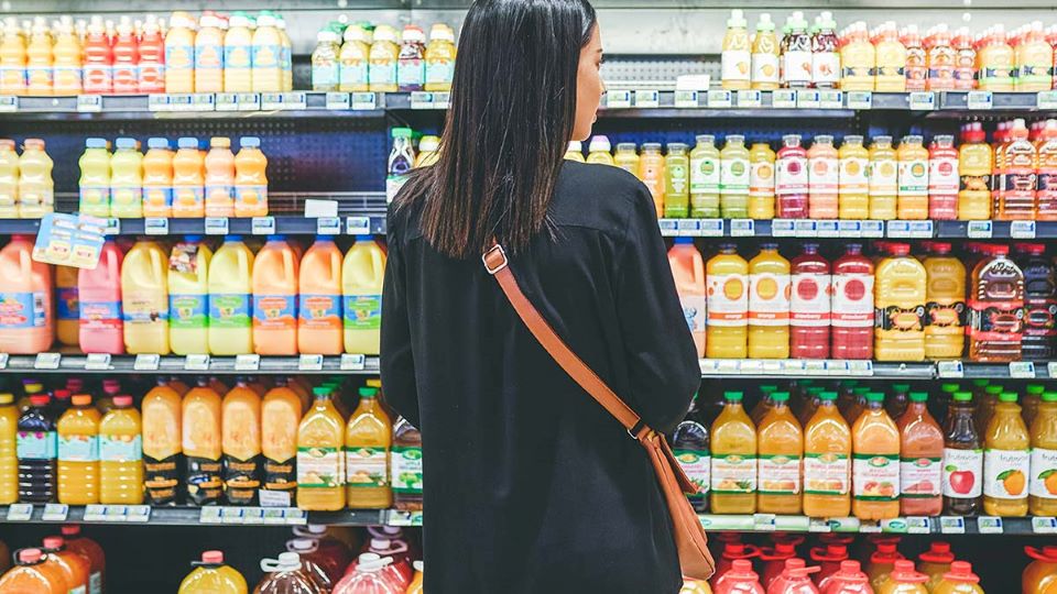 Person in a grocery market looking at shelves of juice