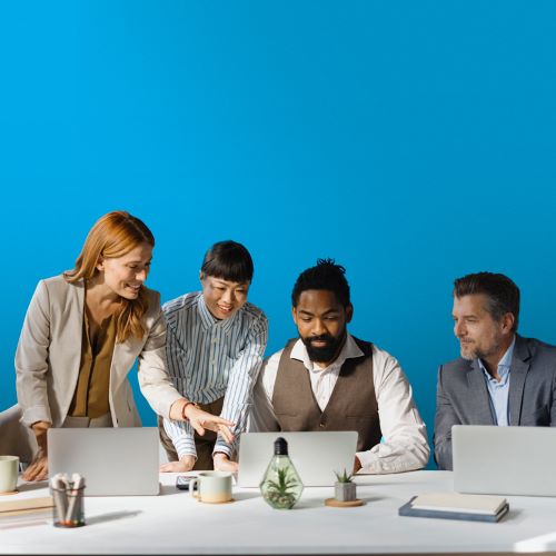 A group of marketers collaborating together with their laptop computers on a blue background