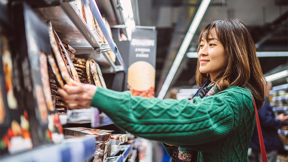 Consumer browsing products in-store, influenced by retail media advertising and digital signage.