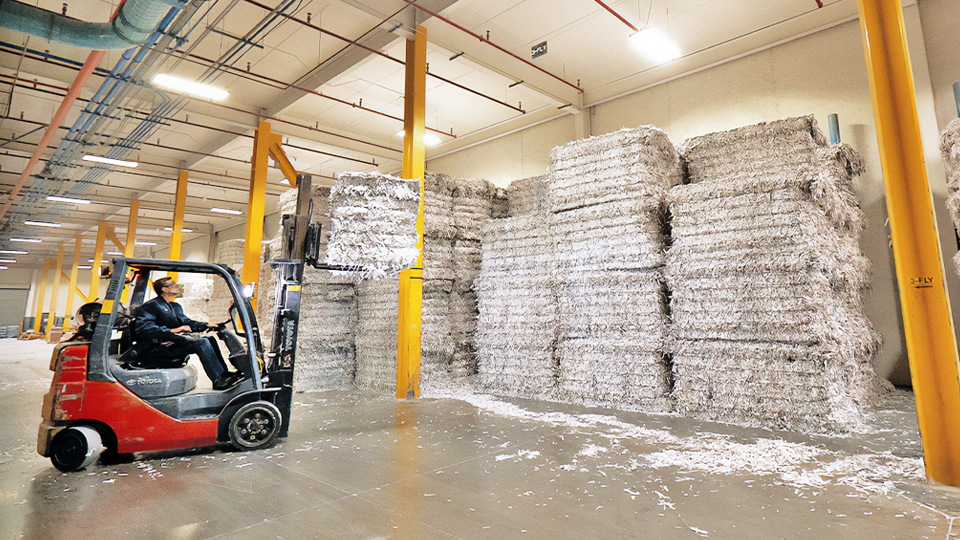 A forklift stacking shredded paper skids in Quad's recycling center