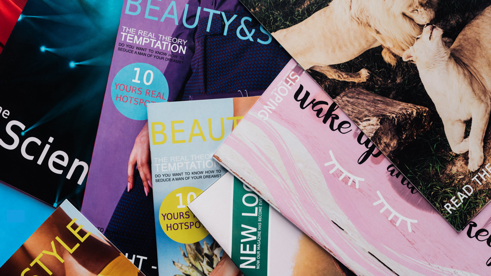 Top view of a pile of different tabloid magazines on surface