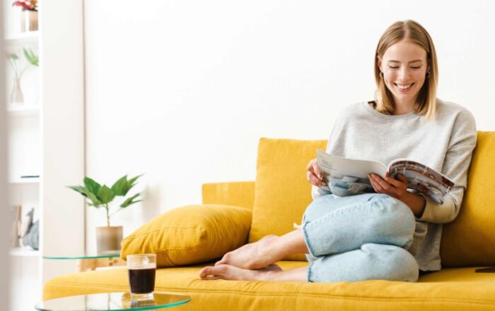 Consumer in her home lounging on her couch while browsing a catalog