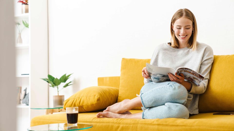 Consumer in her home lounging on her couch while browsing a catalog