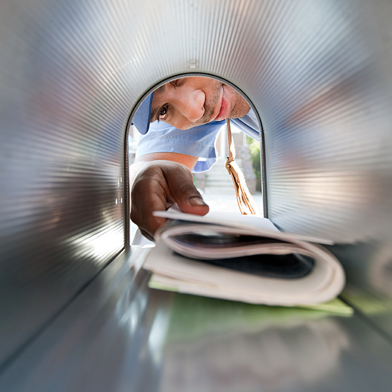 A postal carrier delivering mail to a USPS certified residential mailbox