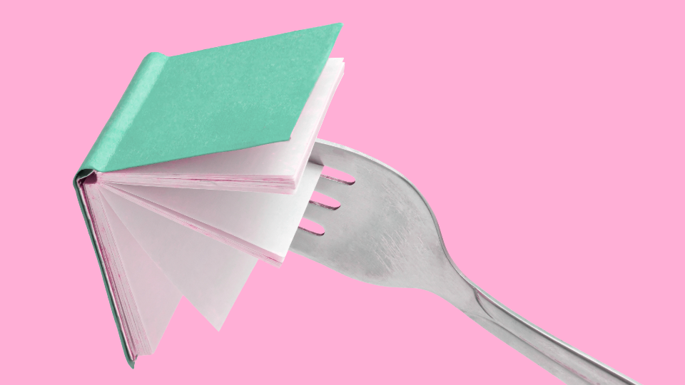 Eating your words with a fork poking an opened book in front of a pink background