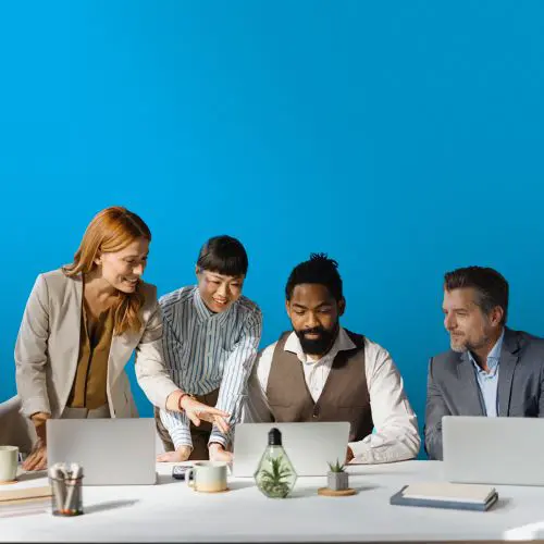A group of marketers collaborating together with their laptop computers on a blue background